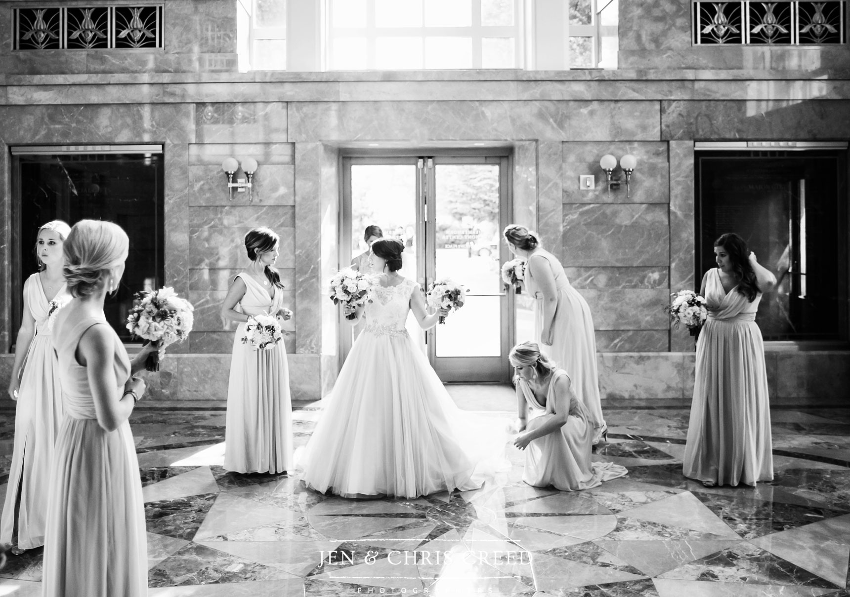 bridesmaids adjusting bride's dress