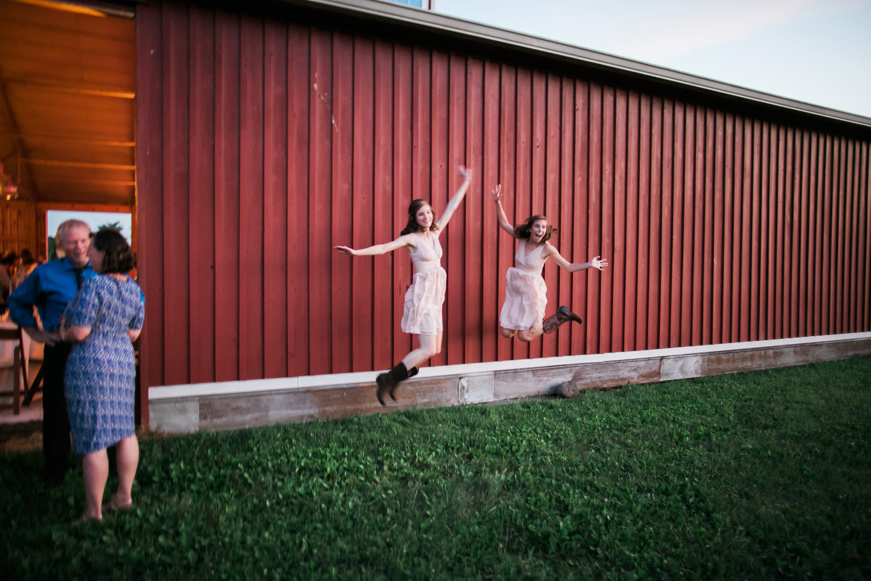 Bridesmaids jumping outside barn